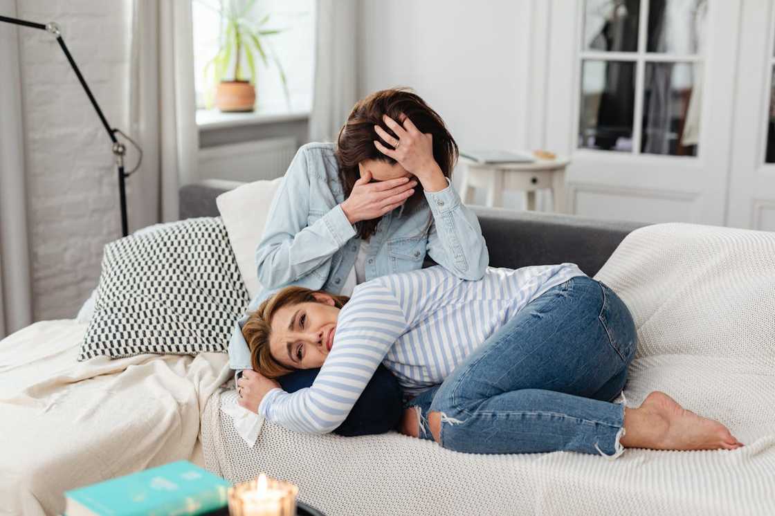 Two women sit on a couch in an emotional moment. Two women sit on a couch in an emotional moment.