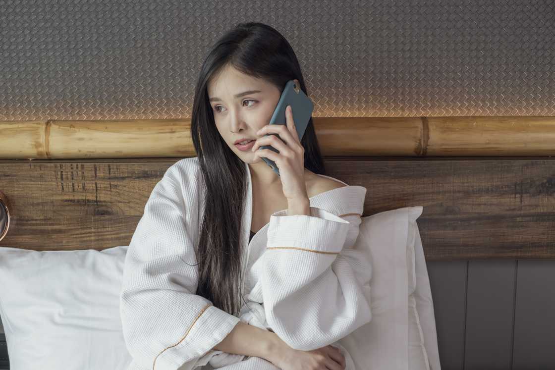 A girl making a call while sitting on a bed