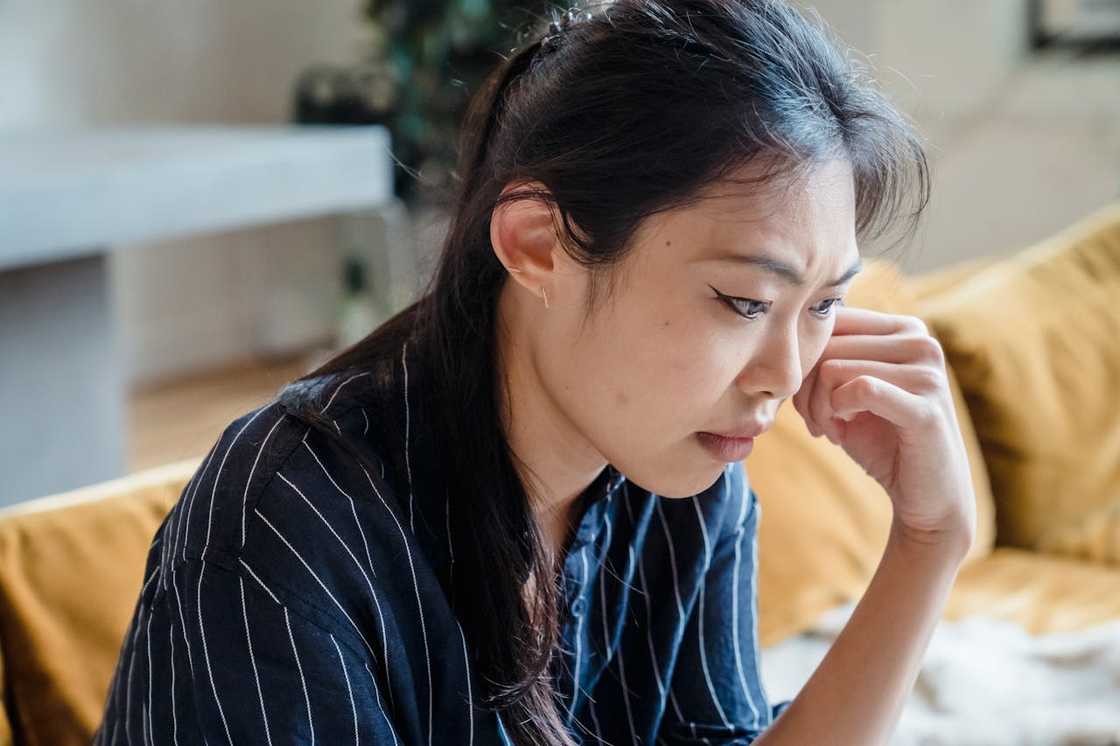 A woman rests her head on her hand in a dimly lit room. A woman rests her head on her hand in a dimly lit room.