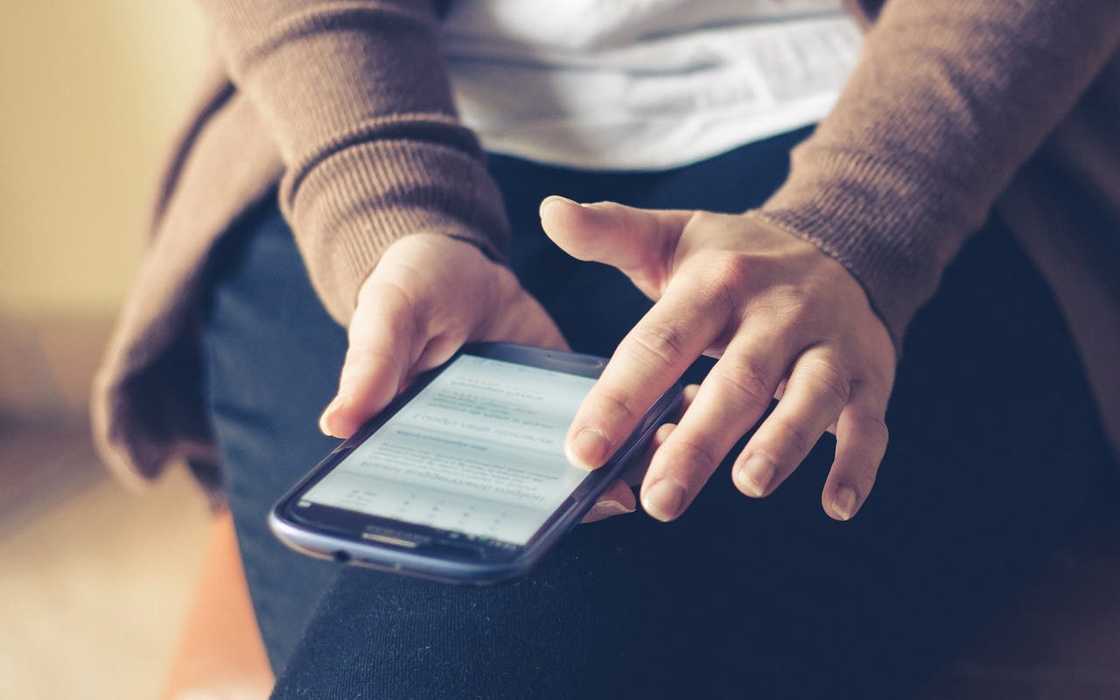 Hands holding a smartphone while scrolling through messages. Hands holding a smartphone while scrolling through messages.