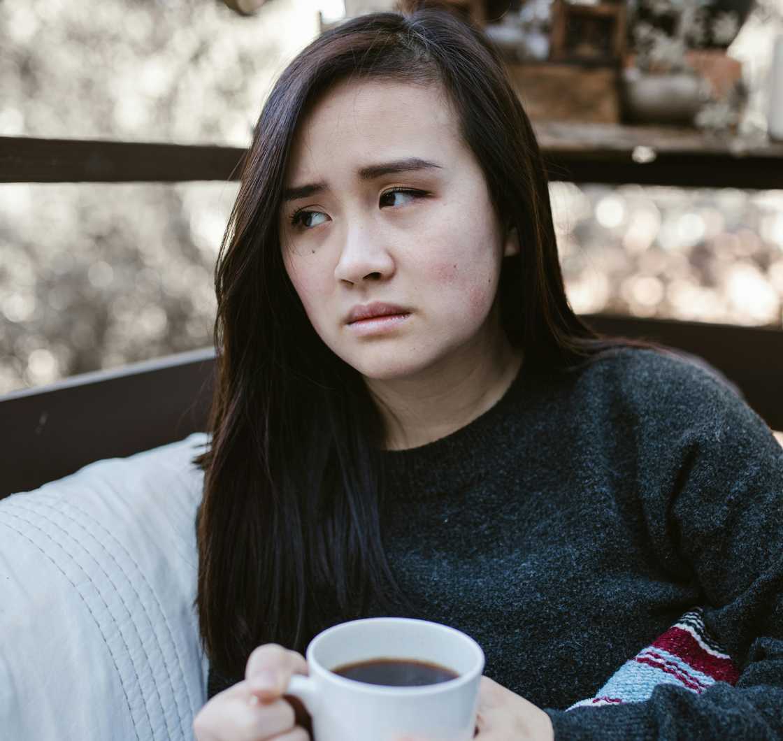 A sad lady holds a cup of coffee