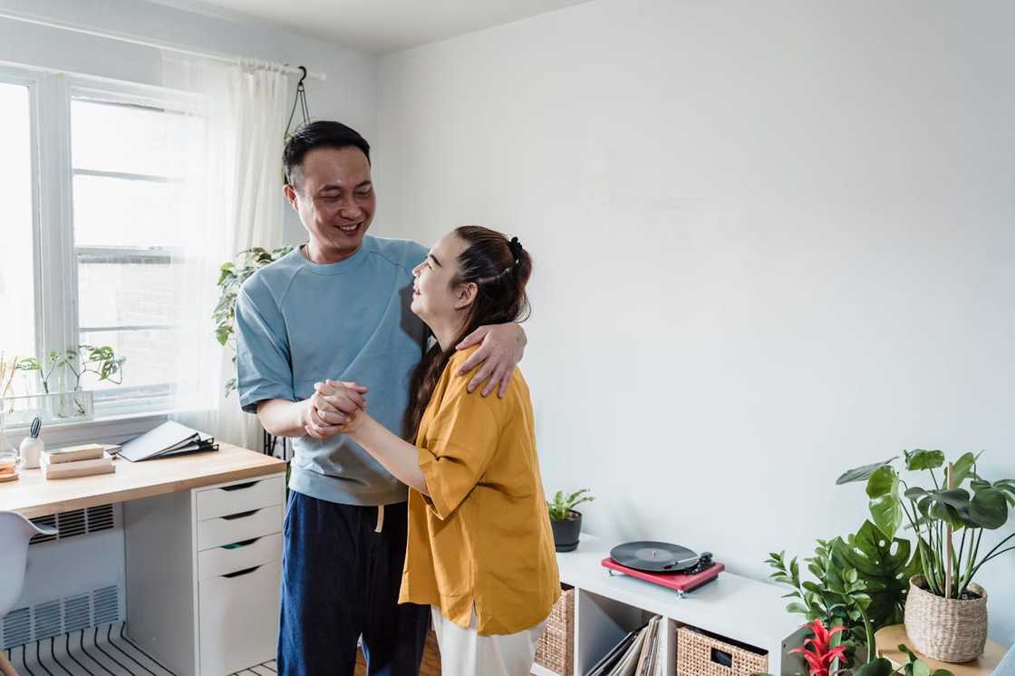 Two people dance together in a cosy, well-lit room.