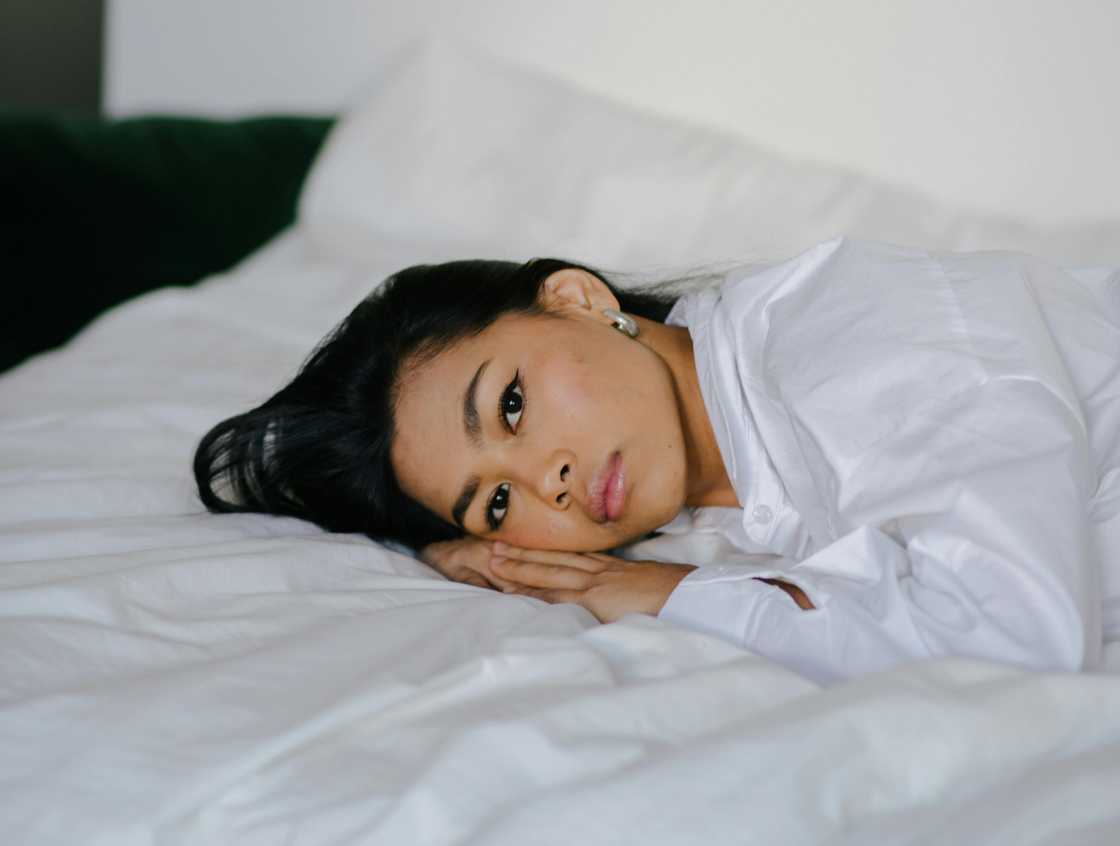 A thoughtful woman lying on the bed A thoughtful woman lying on the bed