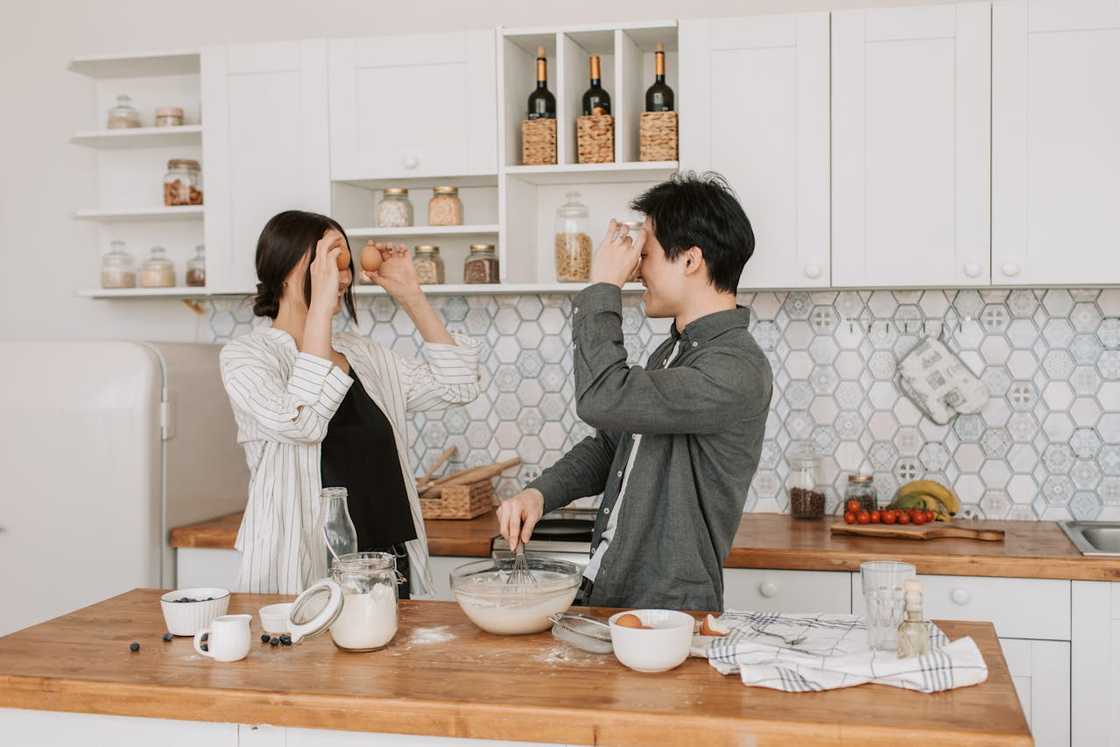 Siblings laughing and cooking together in a small kitchen. Siblings laughing and cooking together in a small kitchen.