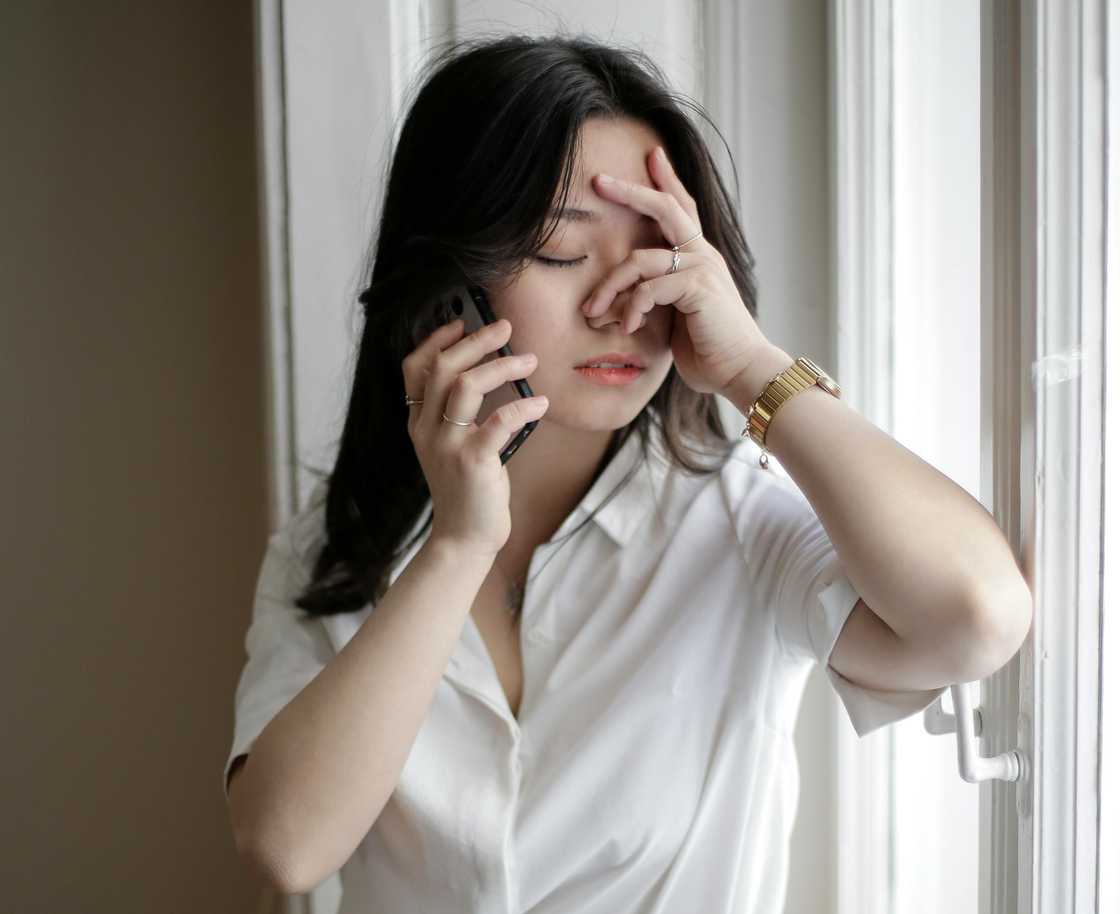 A worried woman holding her forehead while talking on the phone