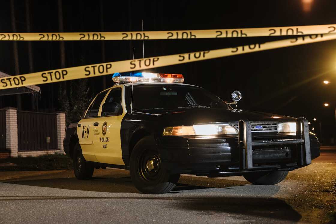 A police car is parked behind caution tape on a quiet street. A police car is parked behind caution tape on a quiet street.