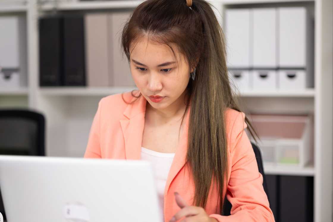 A lady goes through her laptop in office A lady goes through her laptop in office
