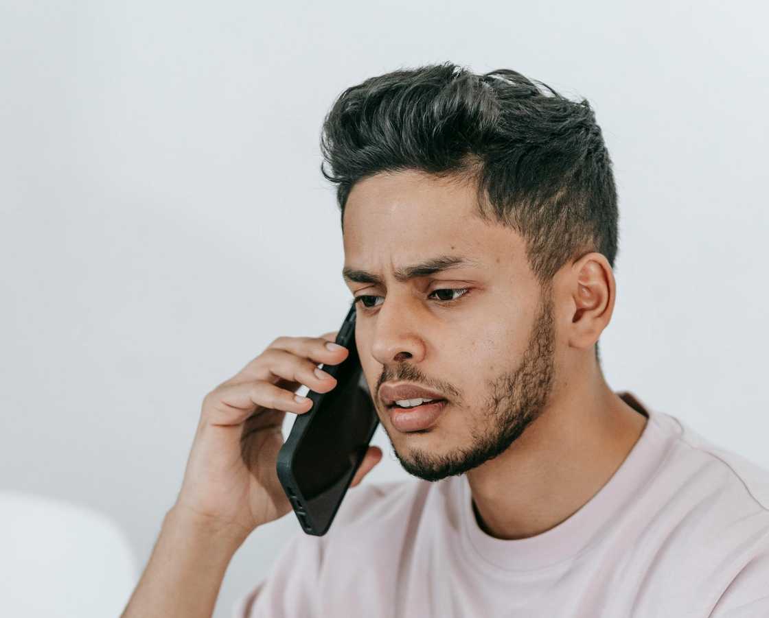 A man listens to a phone call with a serious expression. A man listens to a phone call with a serious expression.