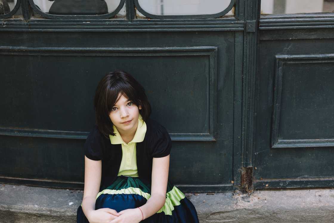 A girl seated next to a gate A girl seated next to a gate