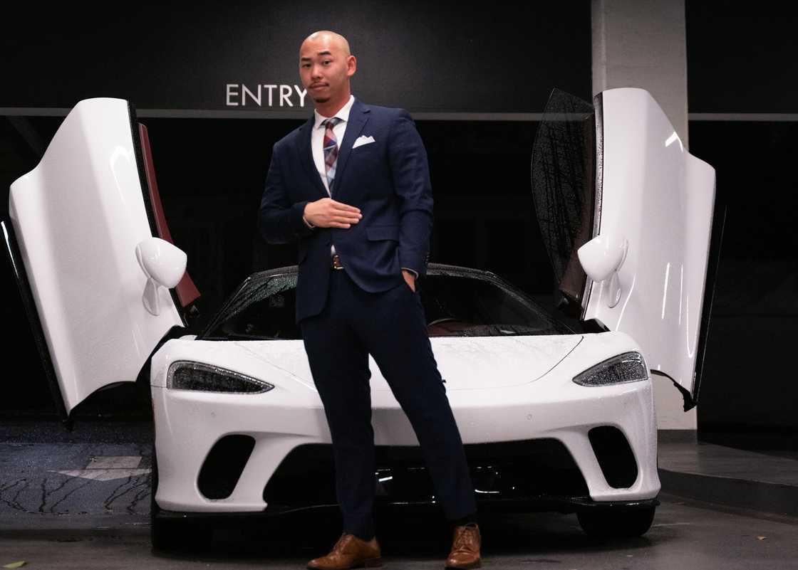 A man posing infront of his luxury car