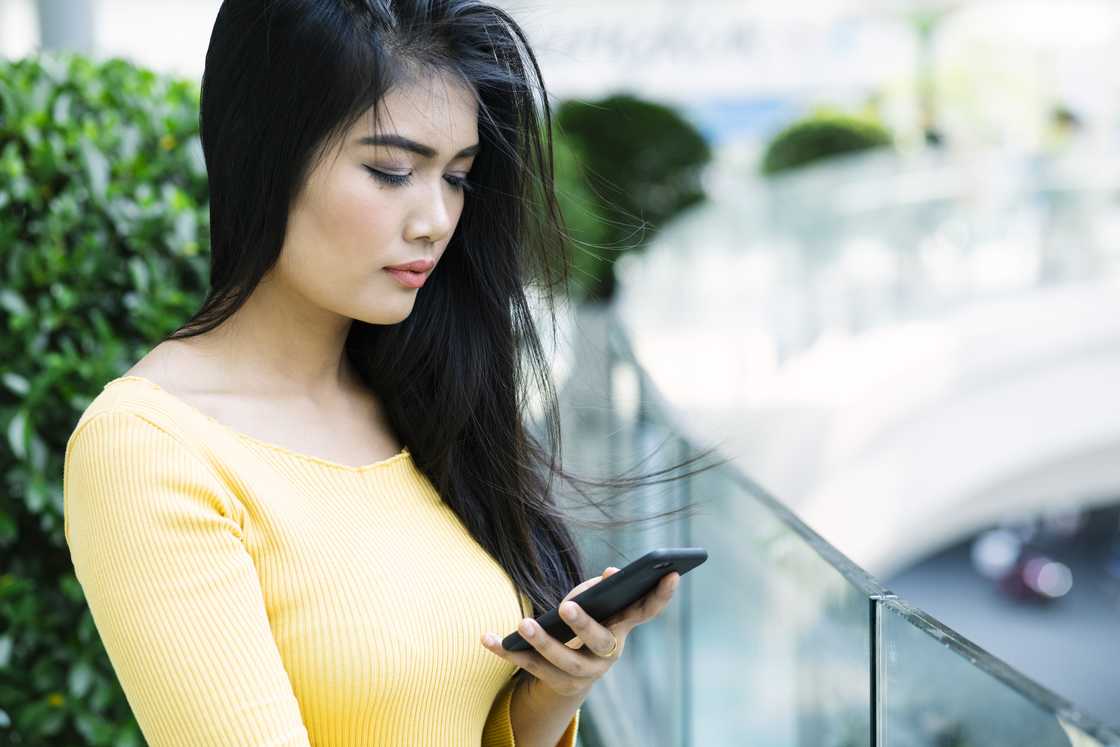 A sad lady texting at the balcony