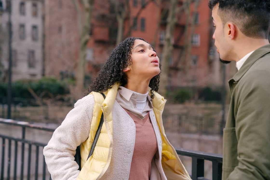 A woman leans forward and confronts a man during an intense argument outdoors.