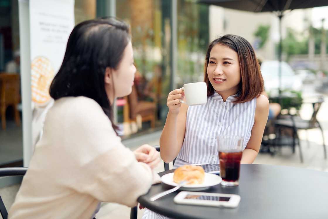 Two ladies at a cafe chatting Two ladies at a cafe chatting