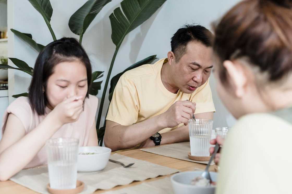 A family sit at a dining table eating a meal together indoors.