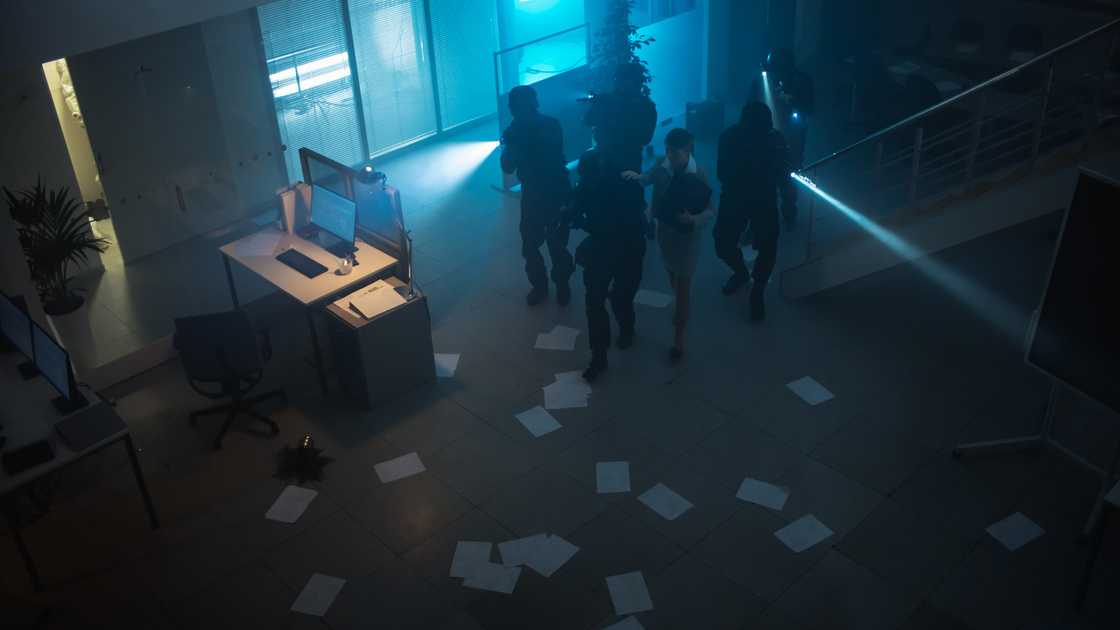 Police enter an office as a businessman freezes in place.