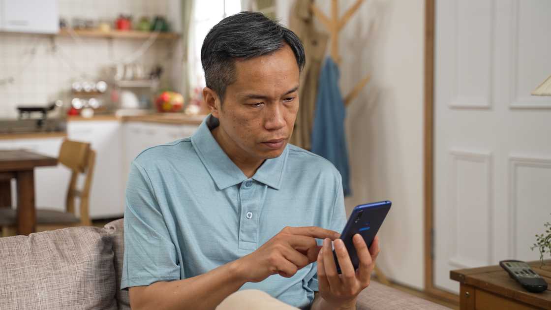 A man using his mobile phone while sitting on couch
