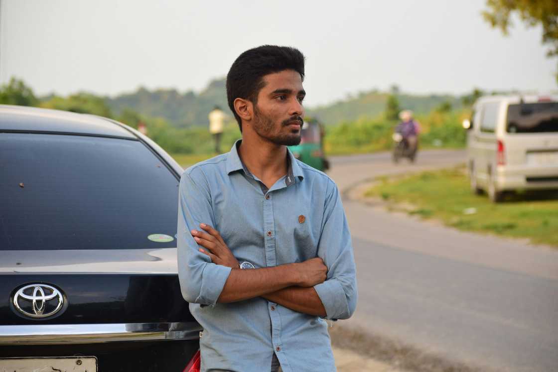 A concerned man standing infront of his car