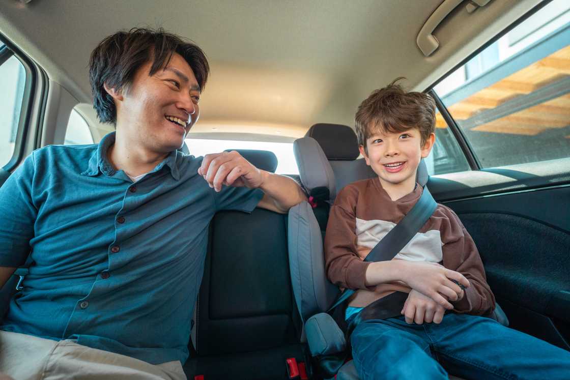 A father and his elementary-age son laughing in a car A father and his elementary-age son laughing in a car