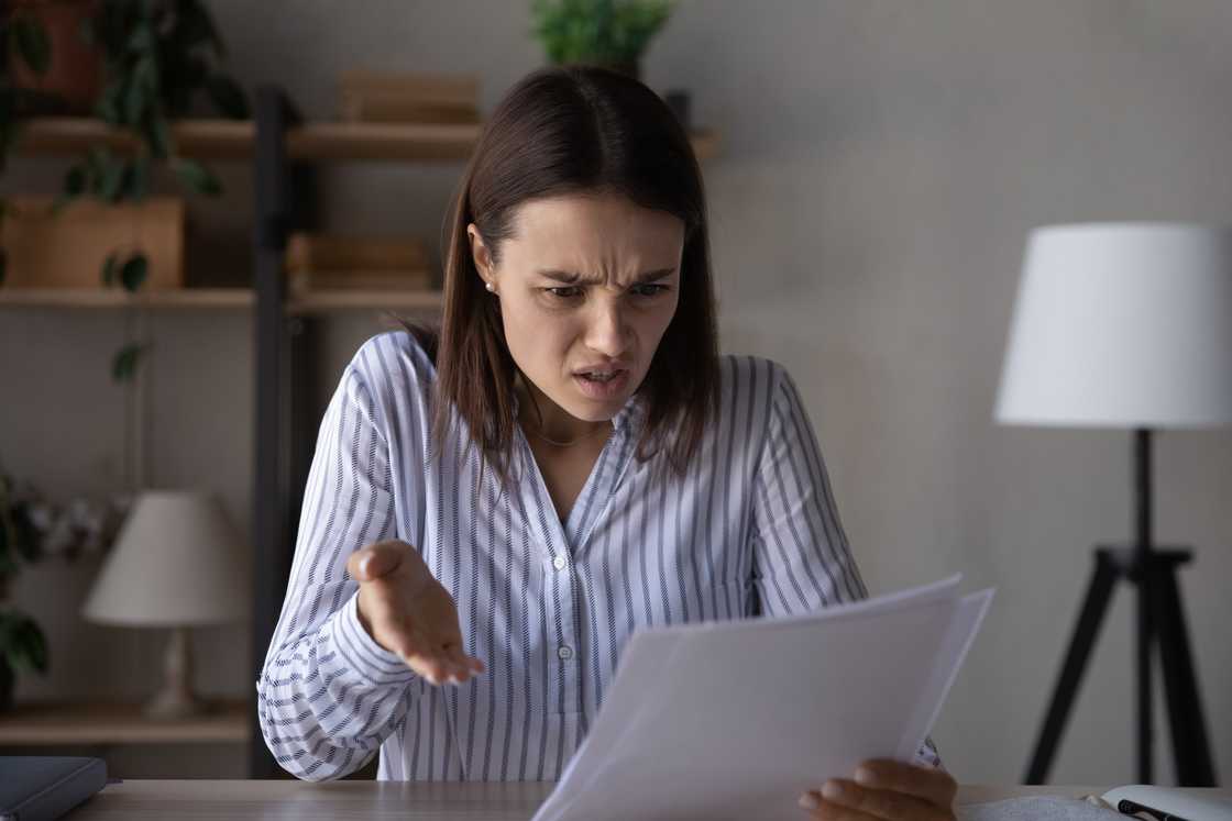 An annoyed and upset young woman reading document An annoyed and upset young woman reading document