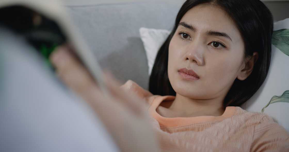 A woman reading a book while lying in bed A woman reading a book while lying in bed