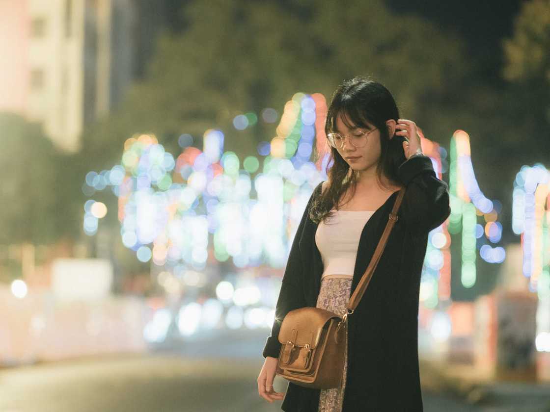A woman walking calmly under the streetlights.