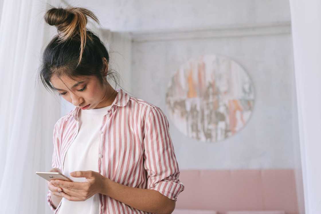 A young woman scrolls through her smartphone at home. A young woman scrolls through her smartphone at home.