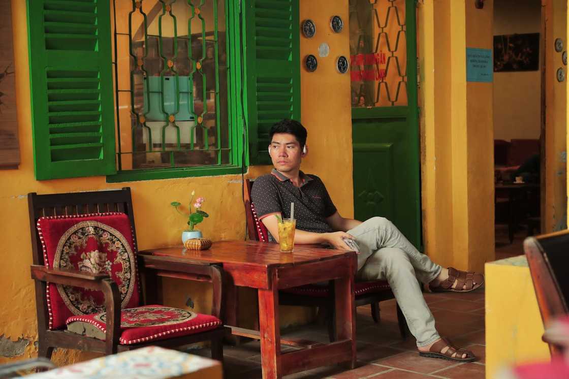 A man sits at an outdoor café table.