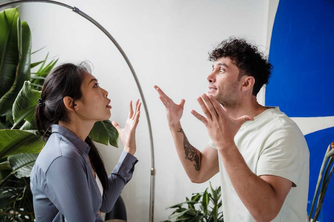 A couple argues indoors with expressive hand gestures. A couple argues indoors with expressive hand gestures.