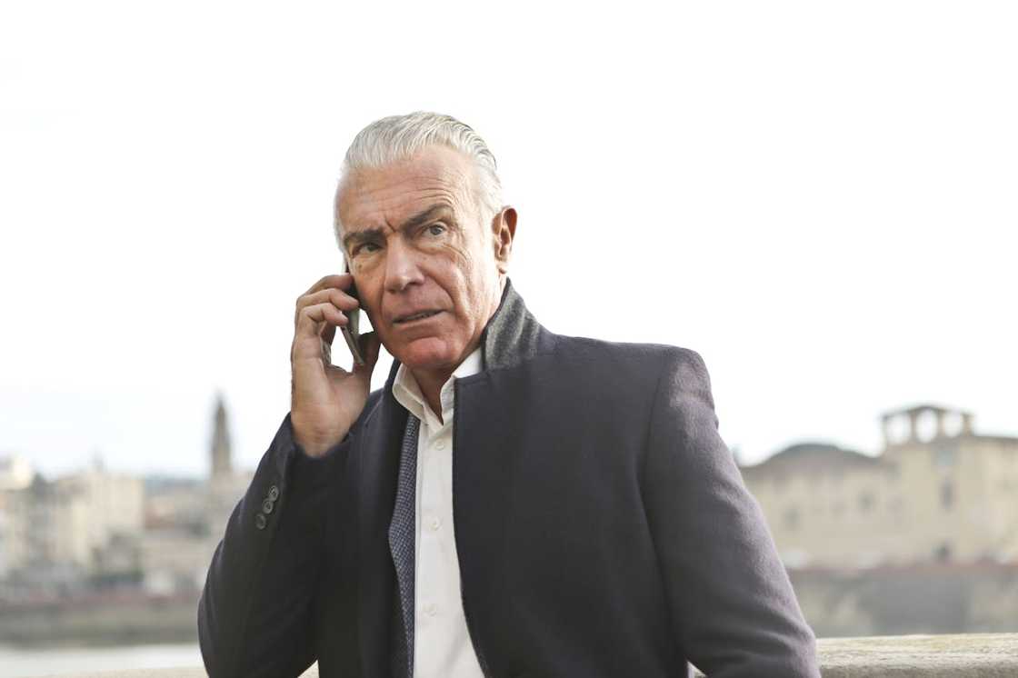 Older businessman speaking on a mobile phone outdoors. Older businessman speaking on a mobile phone outdoors.