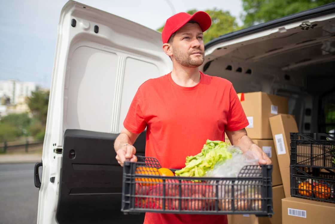 A man unloading crates of fresh vegetables from a delivery van. A man unloading crates of fresh vegetables from a delivery van.