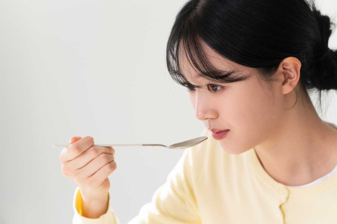 A young woman eating using a spoon