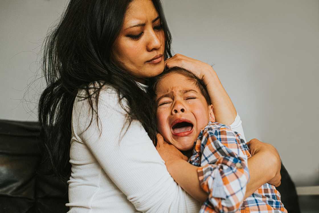 A mother holds her crying son A mother holds her crying son