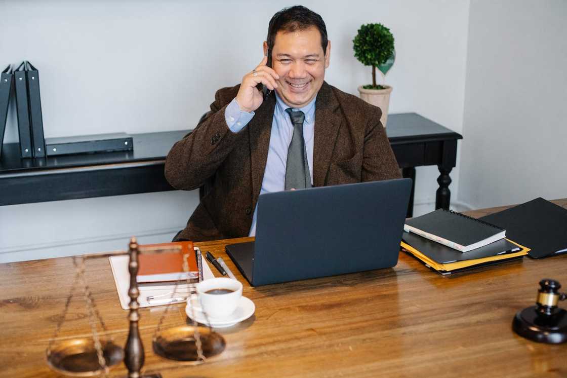 A happy lawyer talks on the phone in his office.