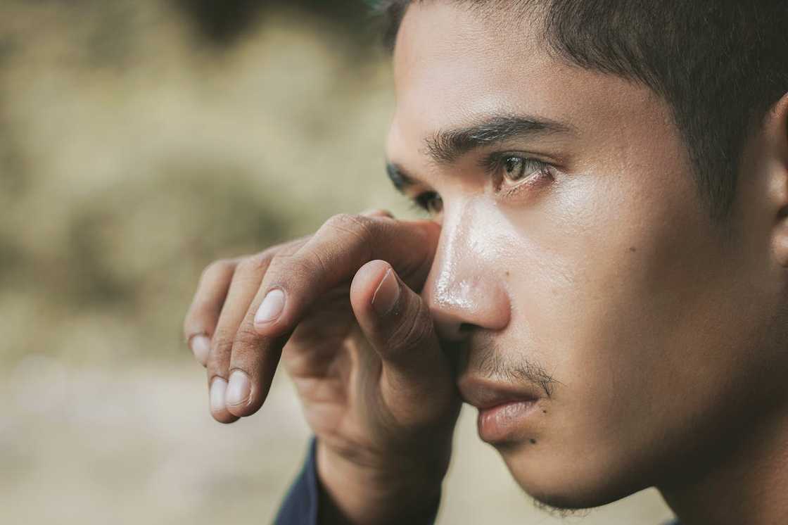 A close-up of a man wiping tears. A close-up of a man wiping tears.