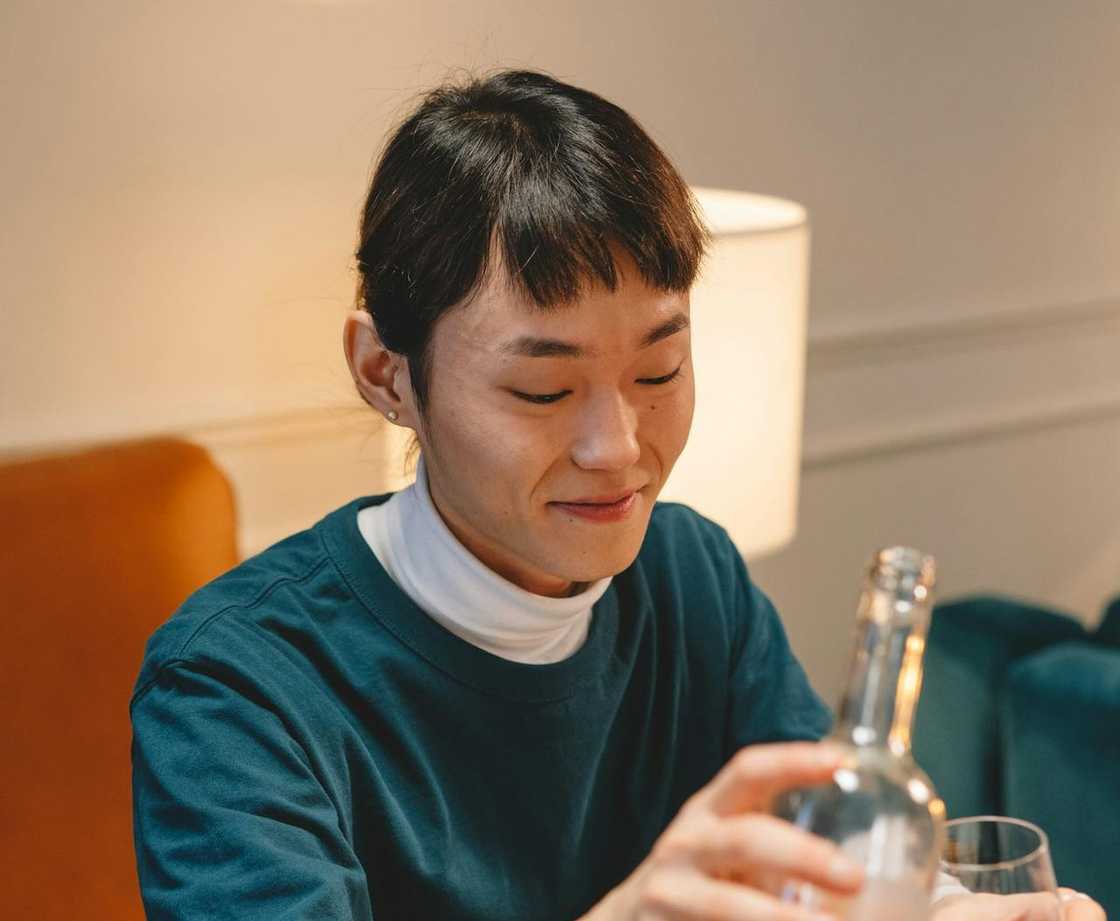 A woman smiling while pouring a drink at a table.