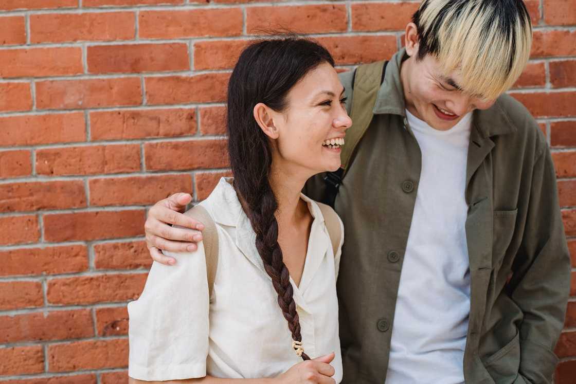 A young couple smiling and talking outdoors.