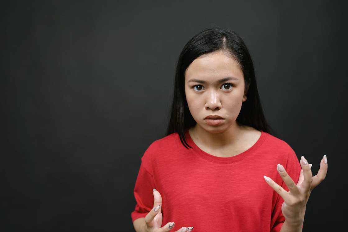 A young woman in a read shirt loos pensive.
