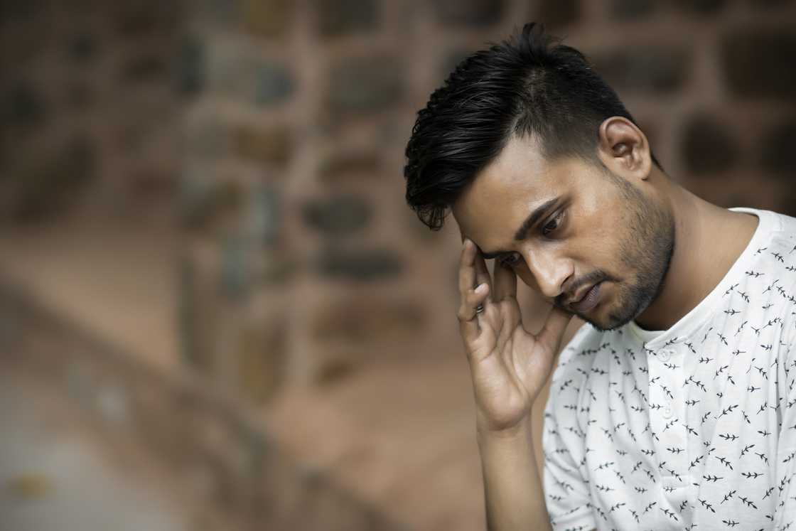 An ashamed man rubbing his head