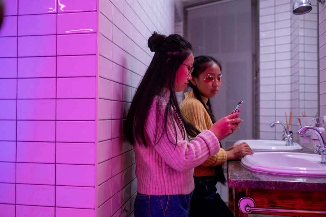 Two women fixing makeup in a restroom. Two women fixing makeup in a restroom.