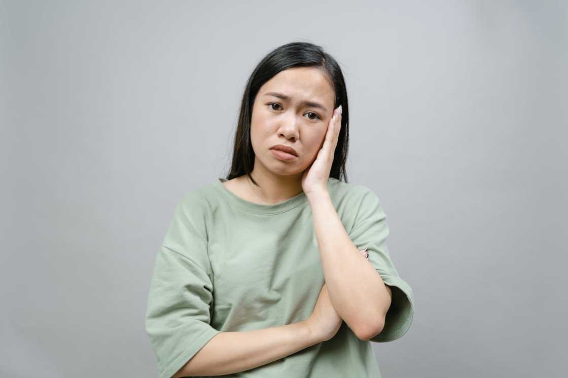 A woman in a green crew neck T-shirt looks dejected.