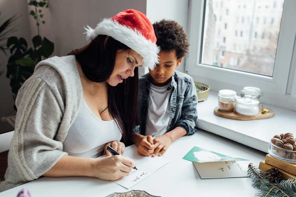 A woman writing a note beside a child. A woman writing a note beside a child.