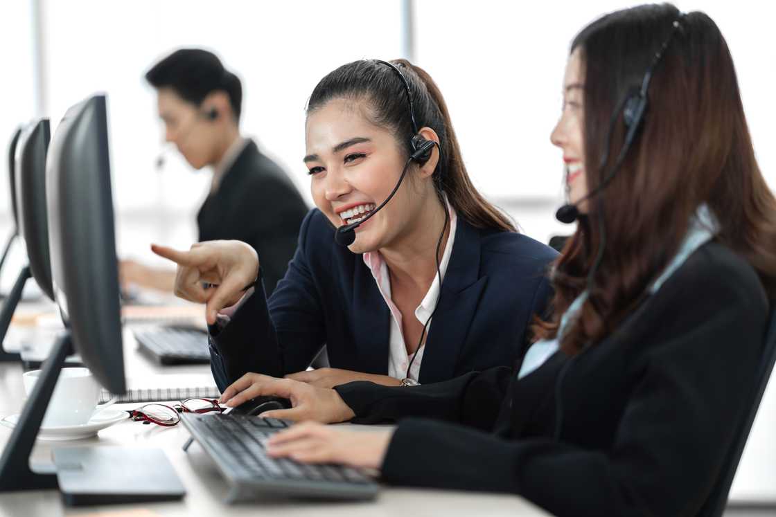 Call centre agents smile and chat between calls on the production floor. Call centre agents smile and chat between calls on the production floor.