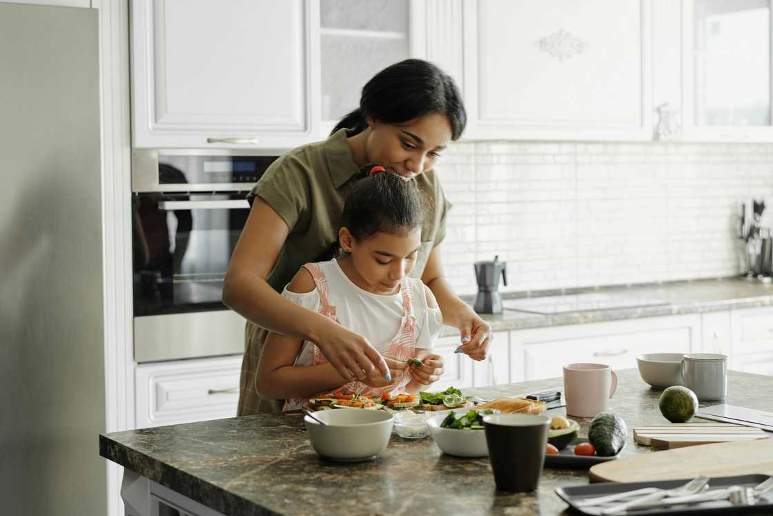 A woman cooking with a young child in the kitchen