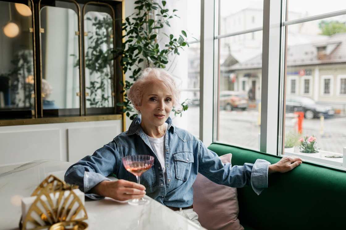 An older woman holding a drink in a café.