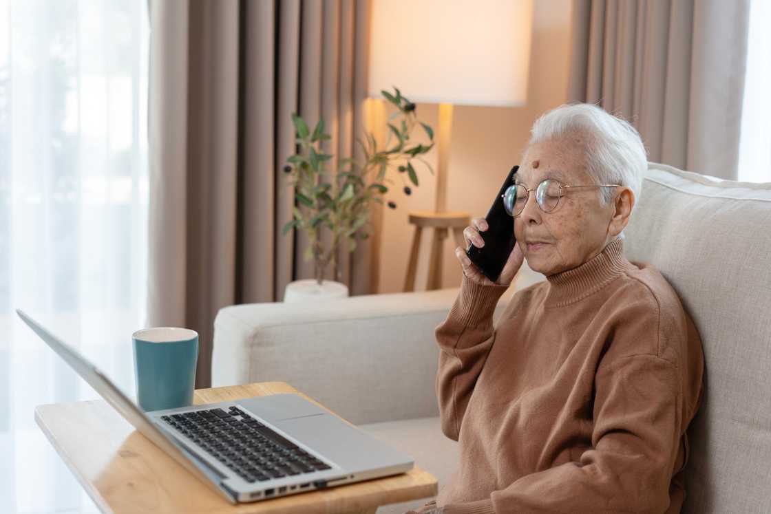 An elderly woman is making a call
