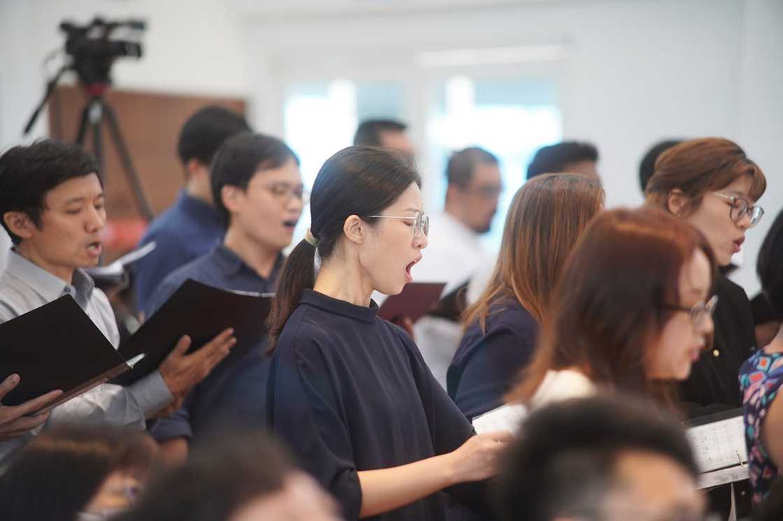 A church choir sings a song from a book. A church choir sings a song from a book.