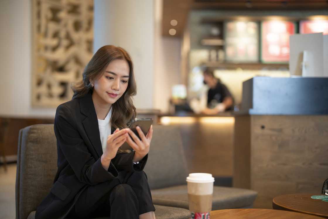 A lady is using her phone in a cafe