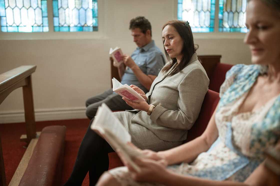 Two women and a man sit quietly during a church meeting. Two women and a man sit quietly during a church meeting.