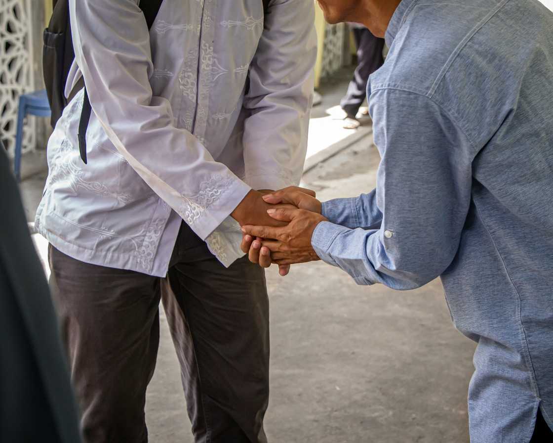 Two people shake hands outdoors.