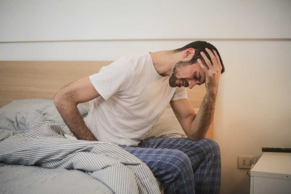 A man in sleepwear holds his head in pain. A man in sleepwear holds his head in pain.